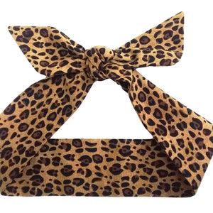 May include: A brown and black leopard print headband with a bow in the front.