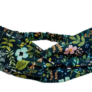 May include: A dark green headband with a floral pattern. The headband is made of a soft, stretchy fabric and has a twisted design.