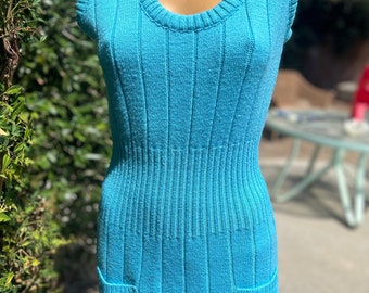 May include: A sleeveless, turquoise blue knitted mini dress with a scoop neck and two pockets.