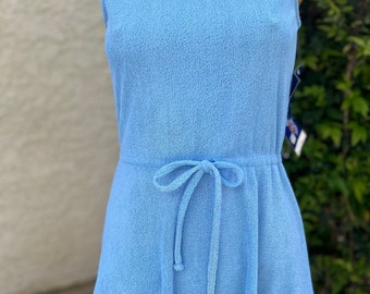 May include: A light blue sleeveless dress with a drawstring waist. The dress is made of a soft, textured fabric.