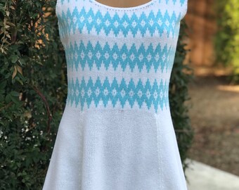 May include: A white sleeveless knit dress with a blue and white geometric pattern. The dress has a scoop neck and a flared skirt.