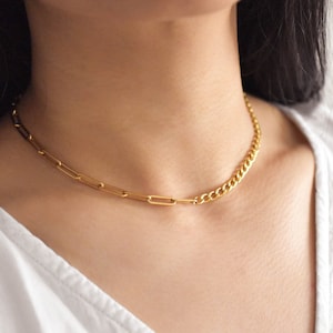 May include: A gold chain necklace with two different styles of links. One side features a curb chain and the other side features a paperclip chain.