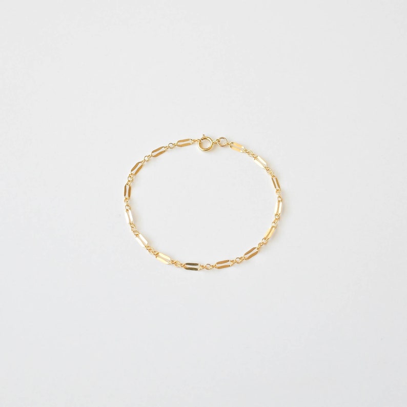 Peut inclure: Un bracelet en cha&icirc;ne dor&eacute;e avec un design d&eacute;licat de maillons rectangulaires.