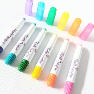May include: A set of eight colorful chalk markers with white barrels and colorful caps. The markers are labeled "Chalk Crayon".