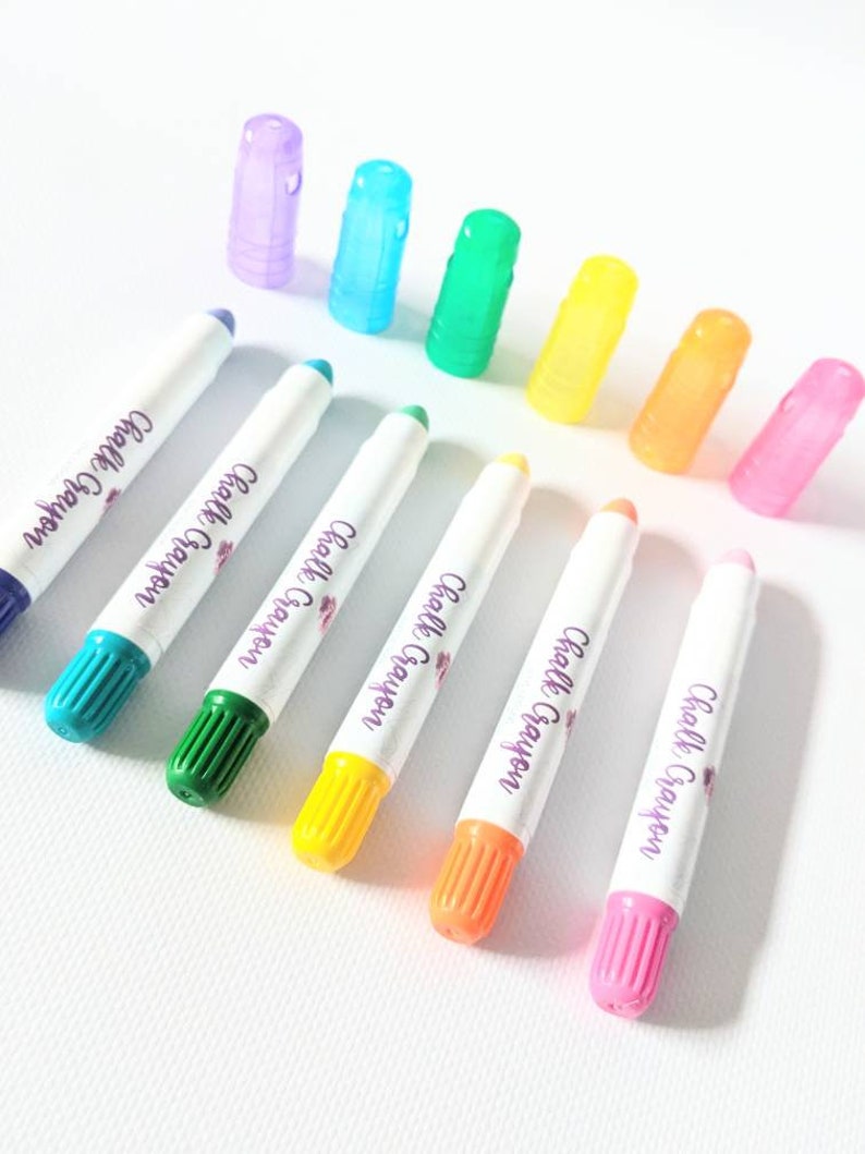 May include: A set of eight colorful chalk markers with white barrels and colorful caps. The markers are labeled "Chalk Crayon".