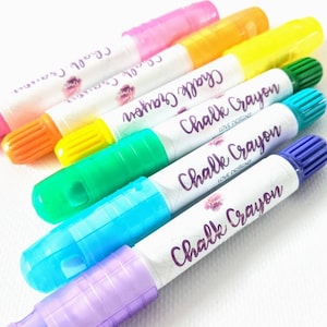 May include: Six colorful chalk crayons with a white label that says "Chalk Crayon Love Designs". The crayons are in the colors pink, yellow, green, blue, and purple.