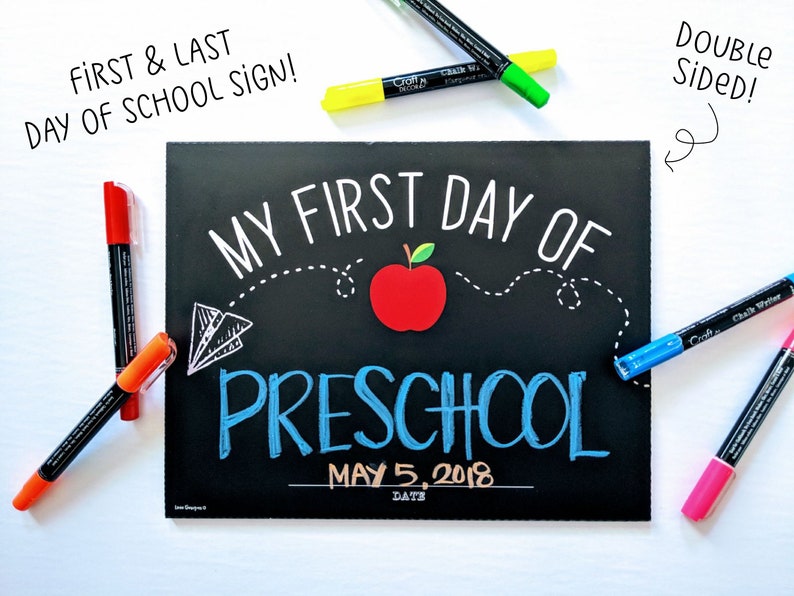 May include: A double-sided chalkboard sign for the first and last day of preschool. The black sign features white and blue lettering that reads "My First Day of Preschool" with a red apple graphic. Includes colorful markers.