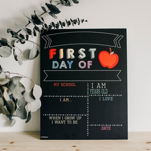 May include: A black chalkboard sign with the text "FIRST DAY OF" in rainbow colors and a red apple illustration. The sign has spaces to fill in information about the first day of school, including the student's name, age, favorite things, and future aspirations.