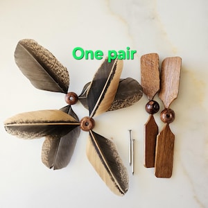 May include: One pair of wooden feather toys with brown feathers and wooden handles. The handles are attached to a wooden bead. Two silver tacks are included.