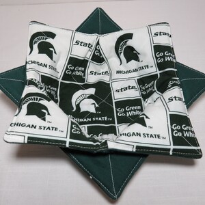 May include: A green and white fabric pot holder with the Michigan State University logo and the words "Go Green Go White" repeated throughout. The pot holder is folded into a star shape.