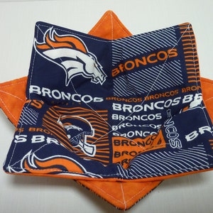 May include: A star-shaped pot holder with a blue and orange fabric design. The fabric features the Denver Broncos logo and the word "Broncos" repeated throughout.