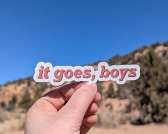 May include: A sticker with the text "it goes, boys" in a red-brown color on a white background.