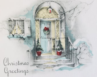 May include: A vintage Christmas card illustration depicts a snow-covered house entrance. The light blue door is adorned with a wreath and a red bow. Two small Christmas trees in red pots flank the steps. The words "Christmas Greetings" are written in cursive.
