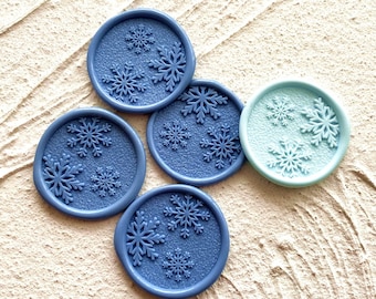 May include: Five blue wax seals with snowflake designs and one light blue wax seal with snowflake designs.