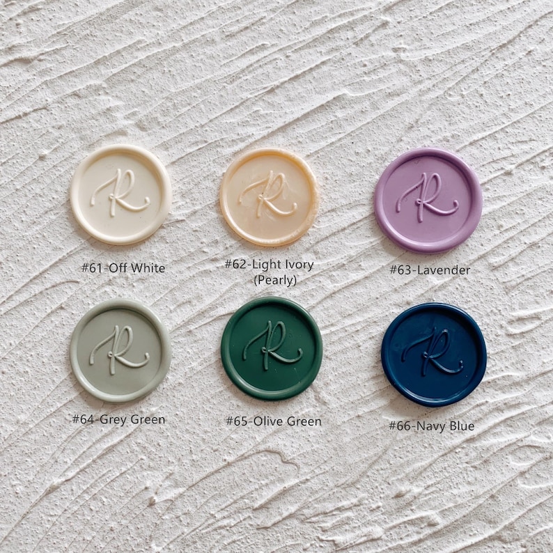 May include: A collection of six wax seals in various colors, each embossed with the letter "R". Colors include off-white, light ivory, lavender, grey green, olive green, and navy blue. Each seal has a corresponding color name and number.