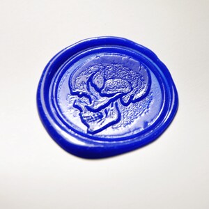 Op de afbeelding: Een blauwe waszegel met een reli&euml;f van een schedel.
