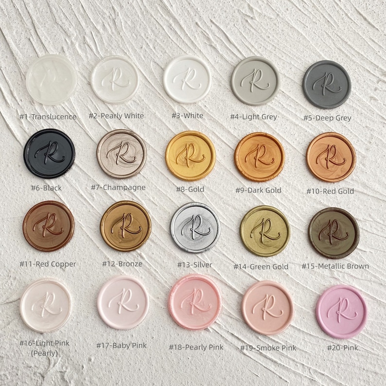 May include: A collection of twenty wax seal stamps in various colors, including translucent, white, gray, black, gold, and pink. Each seal features the letter "R" in a script font. The colors are labeled with numbers and names.