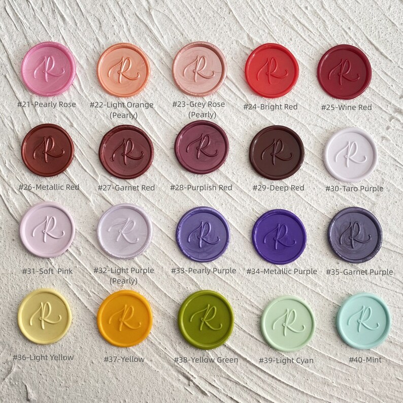 May include: A collection of colorful wax seals in various shades, including pink, orange, red, purple, yellow, and green. Each seal is round with the letter "R" in the center and a unique color name and number.