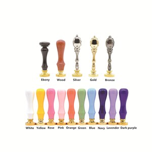 Op de afbeelding: Een set van 13 waszegelstempels in verschillende kleuren en afwerkingen, waaronder ebbenhout, hout, zilver, goud, brons, wit, geel, roze, roze, oranje, groen, blauw, marine, lavendel en donkerpaars. De stempels zijn in twee rijen gerangschikt, waarbij de eerste rij de meer traditionele afwerkingen laat zien en de tweede rij de meer kleurrijke afwerkingen.