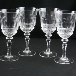 May include: Set of four clear glass wine glasses with etched designs. The glasses have a tall, slender stem and a round bowl.