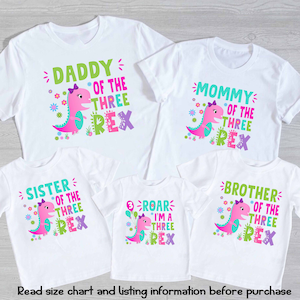 May include: Set of five white t-shirts with a pink dinosaur graphic and text that reads "Daddy of the Three Rex", "Mommy of the Three Rex", "Sister of the Three Rex", "Brother of the Three Rex", and "Roar I'm a Three Rex".