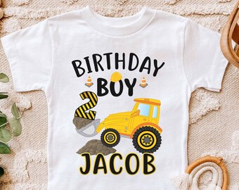 May include: White t-shirt with a yellow construction vehicle graphic, the number 2, and the text "Birthday Boy" and "Jacob".