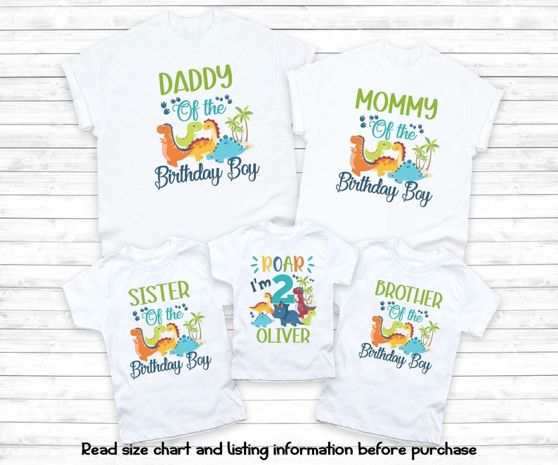 May include: Set of four white t-shirts with dinosaur graphics and text. The shirts say "Daddy of the Birthday Boy", "Mommy of the Birthday Boy", "Sister of the Birthday Boy", and "Brother of the Birthday Boy". One shirt also says "Roar I'm 2 Oliver".