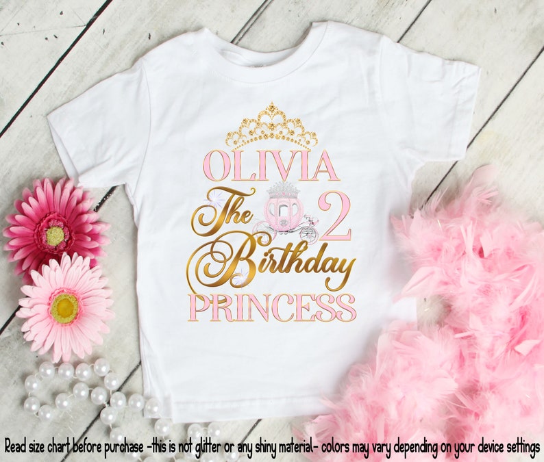 May include: White t-shirt with a gold crown, pink carriage, and the text "OLIVIA The 2 Birthday PRINCESS".