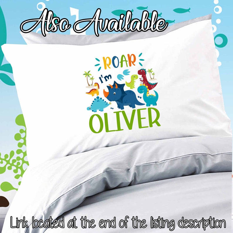 May include: White pillowcase with a dinosaur design. The design features a blue dinosaur with the text "Roar I'm Oliver" in green, blue, orange, and yellow.