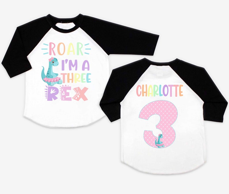 May include: Two white and black baseball shirts with a dinosaur theme. One shirt says "Roar I'm a Three Rex" with a pink dinosaur. The other shirt says "Charlotte" with a pink number 3 and a small dinosaur.