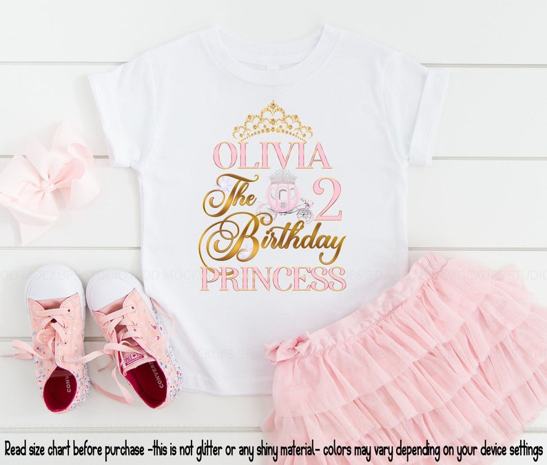 May include: A white t-shirt with a pink and gold design that says "Olivia The 2 Birthday Princess". The shirt is paired with a pink tulle skirt.