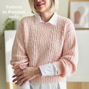 Puede incluir: Un suéter de crochet rosa con un patrón de punto de cable. El suéter tiene un cuello redondo y mangas largas. El patrón está solo en ruso.