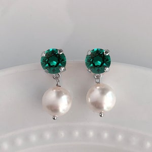 May include: A pair of earrings with a dark green crystal and a white pearl dangling from each earring.