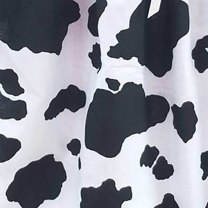 May include: Black and white cow print fabric with a white background and black spots.