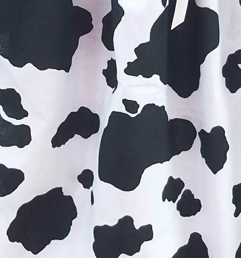 May include: Black and white cow print fabric with a white background and black spots.