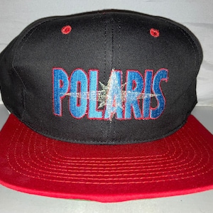 May include: A black and red baseball cap with a white star and the word "POLARIS" embroidered in blue and red.