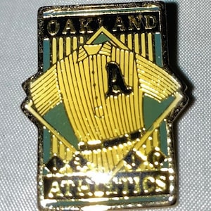 May include: A gold-colored pin with a baseball jersey design. The jersey is yellow and white striped with a green and gold 'A' on the front. The text 'OAKLAND ATHLETICS' is on the bottom of the pin.