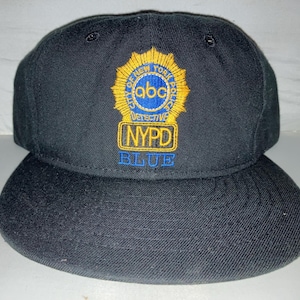 Peut inclure: Casquette de baseball noire avec un logo NYPD brodé en jaune et bleu et le texte "BLUE".