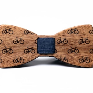May include: A wooden bow tie with a black and white bicycle pattern. The bow tie has a blue adjustable strap.