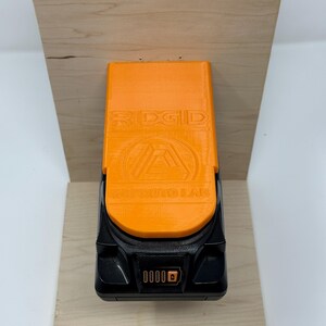 Wall mount battery holder compatible with Ridgid 18V batteries, 3D-printed organizer for workshop or garage. Durable 3D-printed wall mount for Ridgid 18V power tool batteries, easy-install storage bracket. Ridgid 18V battery wall holder and organizer, heavy-duty plastic mount for secure tool battery storage. Compact Orange wall-mounted rack designed to hold Ridgid 18V lithium power tool batteries. Space-saving Ridgid 18Vbattery mount for workshop walls, keeps batteries organized.