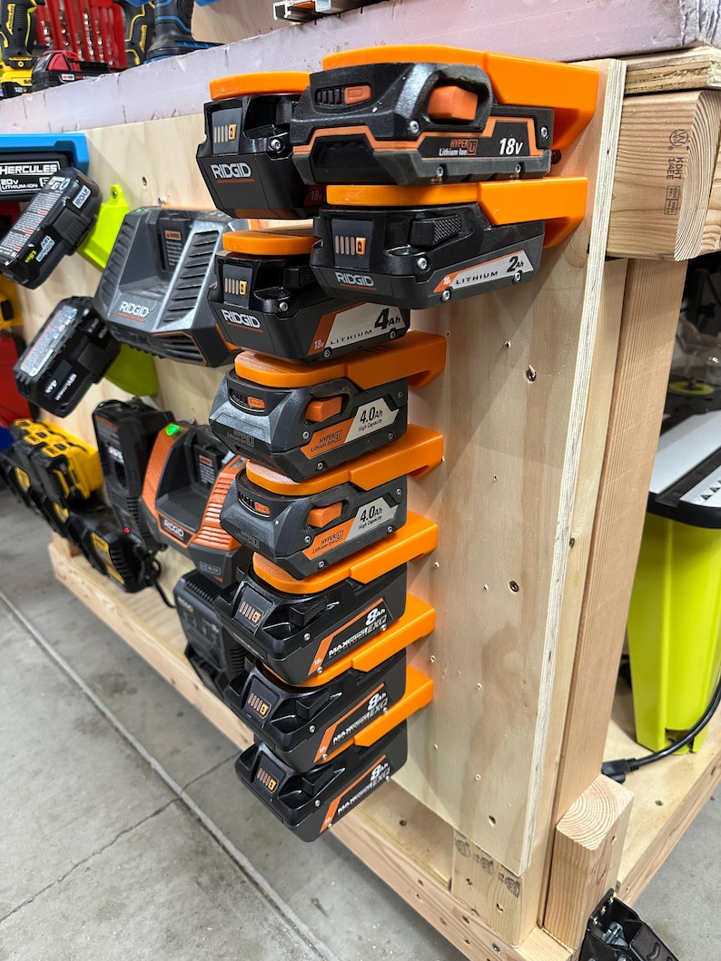 Wall mount battery holder compatible with Ridgid 18V batteries, 3D-printed organizer for workshop or garage. Durable 3D-printed wall mount for Ridgid 18V power tool batteries, easy-install storage bracket. Ridgid 18V battery wall holder and organizer, heavy-duty plastic mount for secure tool battery storage. Compact Orange wall-mounted rack designed to hold Ridgid 18V lithium power tool batteries. Space-saving Ridgid 18Vbattery mount for workshop walls, keeps batteries organized.