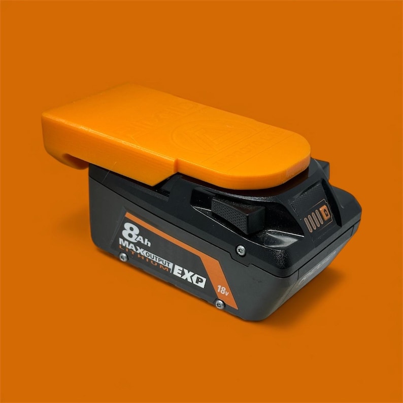 Wall mount battery holder compatible with Ridgid 18V batteries, 3D-printed organizer for workshop or garage. Durable 3D-printed wall mount for Ridgid 18V power tool batteries, easy-install storage bracket. Ridgid 18V battery wall holder and organizer, heavy-duty plastic mount for secure tool battery storage. Compact Orange wall-mounted rack designed to hold Ridgid 18V lithium power tool batteries. Space-saving Ridgid 18Vbattery mount for workshop walls, keeps batteries organized.