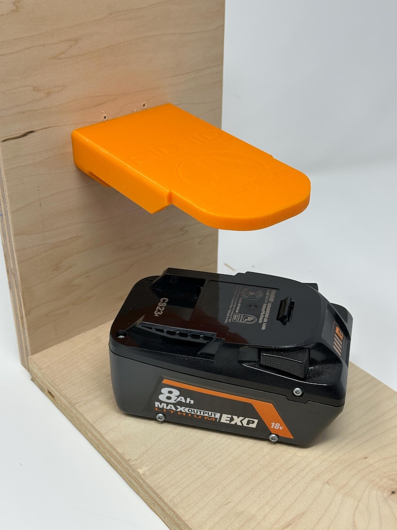 Wall mount battery holder compatible with Ridgid 18V batteries, 3D-printed organizer for workshop or garage. Durable 3D-printed wall mount for Ridgid 18V power tool batteries, easy-install storage bracket. Ridgid 18V battery wall holder and organizer, heavy-duty plastic mount for secure tool battery storage. Compact Orange wall-mounted rack designed to hold Ridgid 18V lithium power tool batteries. Space-saving Ridgid 18Vbattery mount for workshop walls, keeps batteries organized.