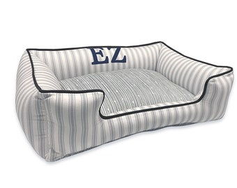 May include: A white and blue striped dog bed with a black border and the initials "EZ" embroidered on the top.