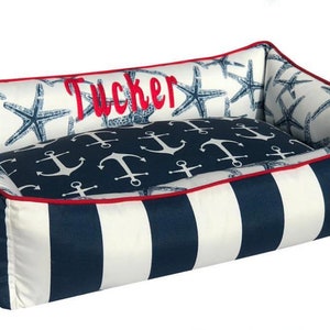 Navy & White Nautical Dog Bed with red trim and monogrammed name with a white background