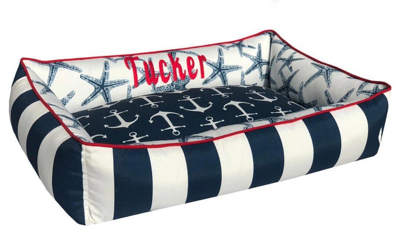 Navy & White Nautical Dog Bed with red trim and monogrammed name with a white background