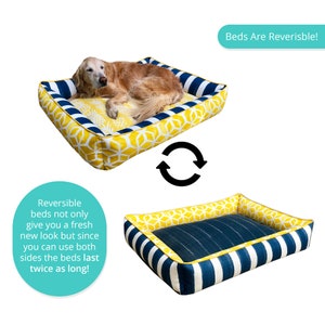 May include: A reversible dog bed with a yellow and blue geometric pattern. The bed is shown with a dog lying on it. The text "Beds Are Reversible!" is shown in a teal box above the bed. The text "Reversible beds not only give you a fresh new look but since you can use both sides the beds last twice as long!" is shown in a teal circle below the bed.