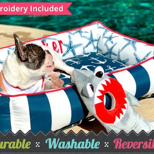 Nautical Pet Bed & Frenchie dog sitting by a pool, with shark stuffed toy close by.