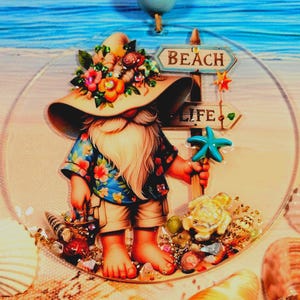May include: A whimsical beach-themed ornament featuring a gnome wearing a floral hat and Hawaiian shirt. The gnome holds a starfish and a basket of shells, with signs reading "Beach" and "Life". The ornament is surrounded by seashells and sand.
