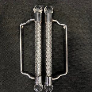 May include: A pair of silver-toned towel bars with clear glass crystal knobs. The bars are twisted and have a decorative design.
